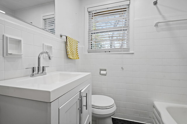 bathroom featuring vanity, a tub, tile walls, and toilet