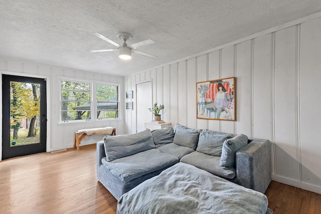 living room featuring ceiling fan, a textured ceiling, and light wood-type flooring