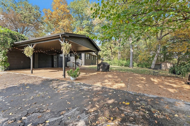 view of front of home featuring a garage, a carport, and a storage shed