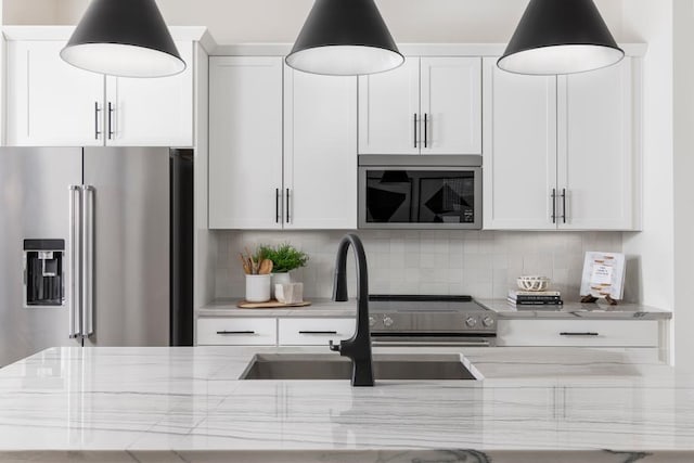 kitchen with white cabinetry, sink, light stone countertops, and appliances with stainless steel finishes