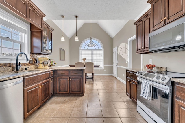 kitchen featuring stainless steel appliances, lofted ceiling, hanging light fixtures, glass insert cabinets, and a sink