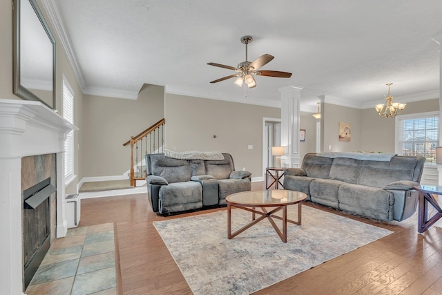 living area with stairs, crown molding, light wood-type flooring, baseboards, and a tile fireplace