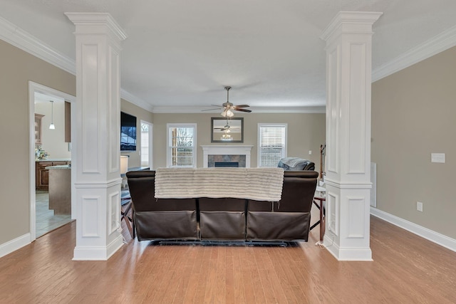 living room with ornamental molding, decorative columns, and a tiled fireplace