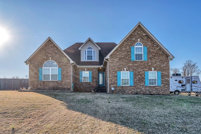 traditional-style home with fence, a front lawn, and brick siding