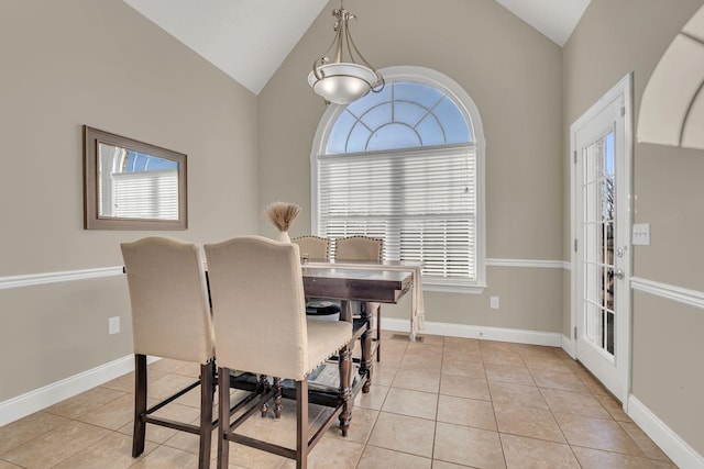 dining room with light tile patterned floors, vaulted ceiling, and baseboards