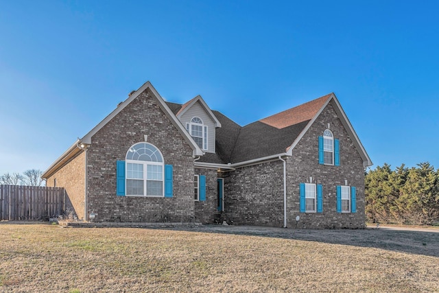 traditional-style home featuring brick siding, a front yard, and fence