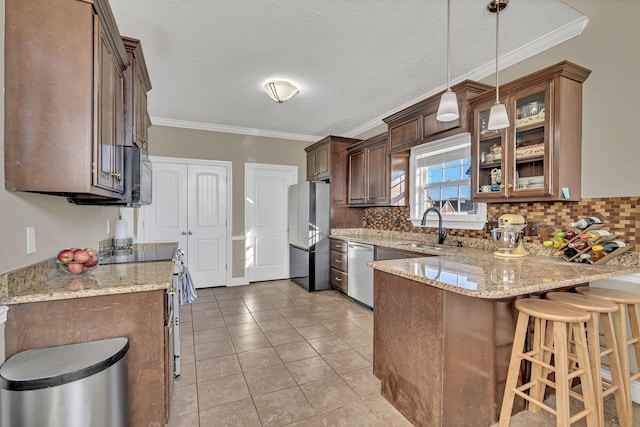 kitchen featuring light stone counters, decorative light fixtures, stainless steel appliances, a sink, and glass insert cabinets