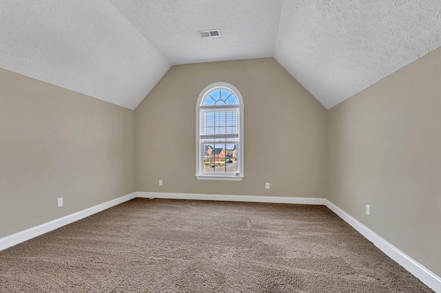 additional living space with baseboards, visible vents, lofted ceiling, carpet, and a textured ceiling