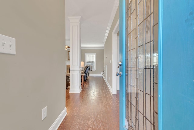 entrance foyer featuring ornamental molding, wood finished floors, decorative columns, and baseboards