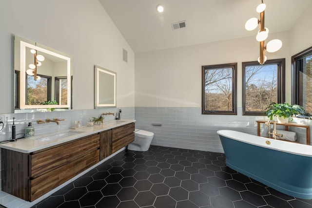 bathroom featuring a bath, a healthy amount of sunlight, tile walls, and toilet