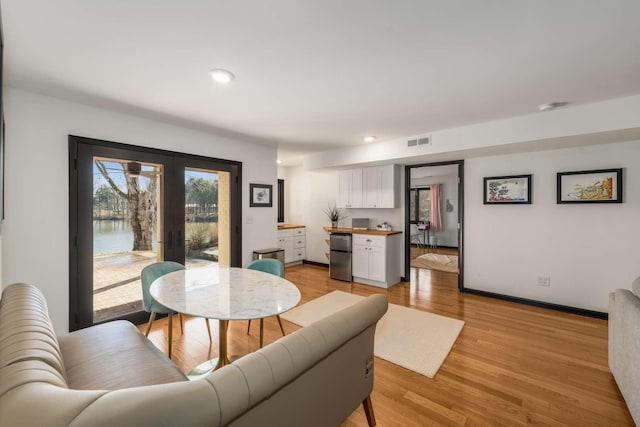 dining space with light hardwood / wood-style floors and french doors