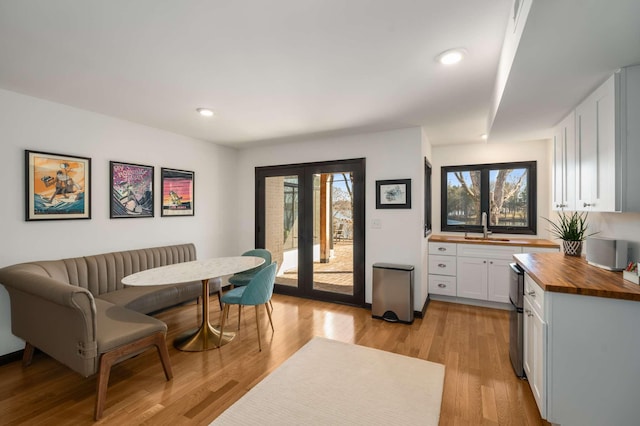 dining area with sink, light hardwood / wood-style floors, and french doors