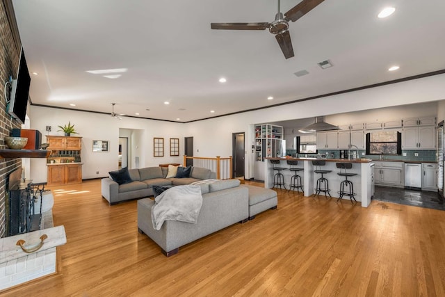 living room featuring ceiling fan, light hardwood / wood-style floors, and a brick fireplace