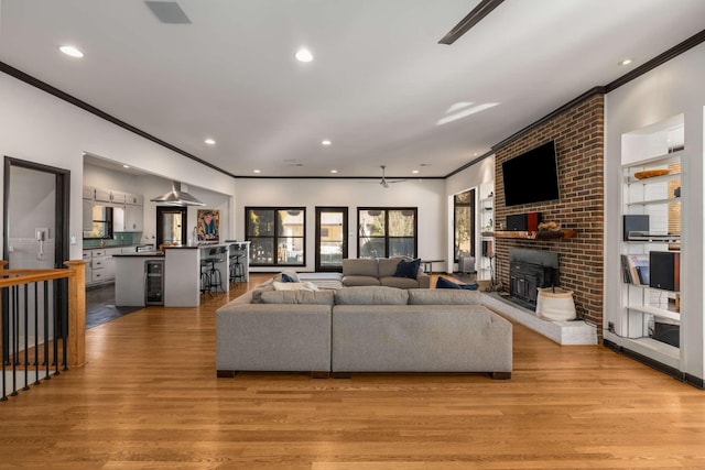 living room featuring ornamental molding, beverage cooler, and light wood-type flooring