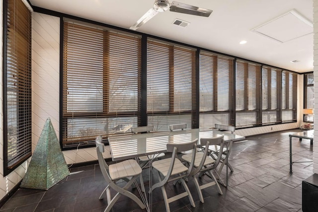 dining space with ceiling fan and wooden walls