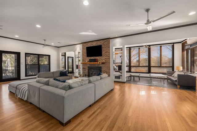 living room featuring ornamental molding, ceiling fan, light hardwood / wood-style floors, and a fireplace