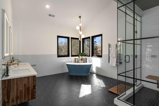 bathroom featuring tile walls, vanity, a towering ceiling, plus walk in shower, and tile patterned flooring