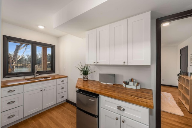 kitchen with white cabinetry, sink, and wooden counters