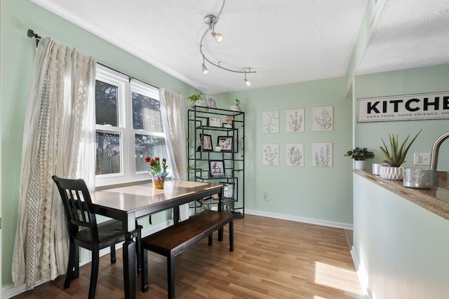 dining area featuring a textured ceiling and light hardwood / wood-style flooring