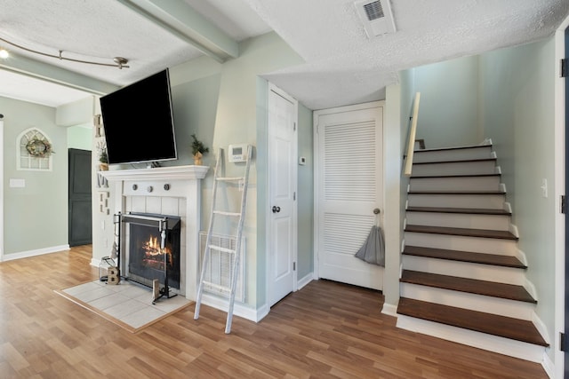 stairs featuring a tile fireplace, hardwood / wood-style floors, and a textured ceiling