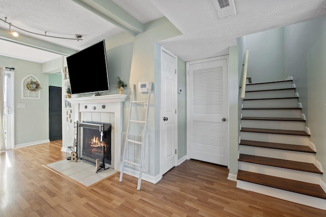 living room featuring a tiled fireplace, hardwood / wood-style floors, and a textured ceiling