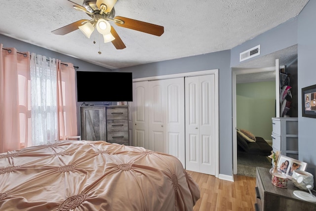 bedroom with light wood-type flooring, a textured ceiling, ceiling fan, and a closet