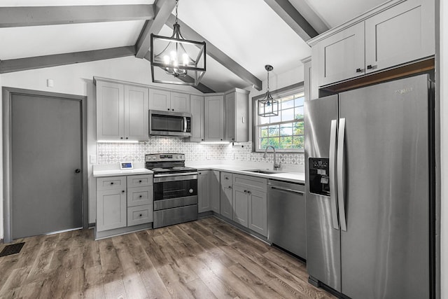 kitchen featuring lofted ceiling with beams, appliances with stainless steel finishes, sink, and hanging light fixtures