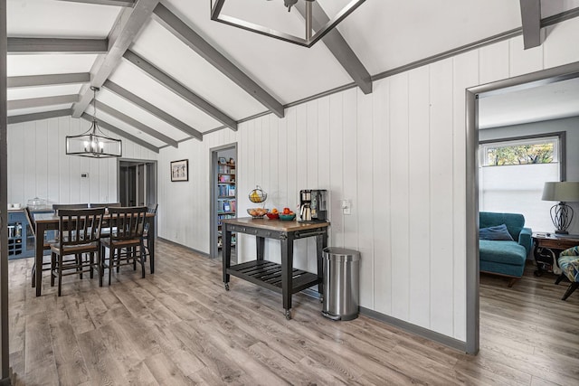 dining room featuring lofted ceiling with beams, hardwood / wood-style flooring, a chandelier, and wood walls