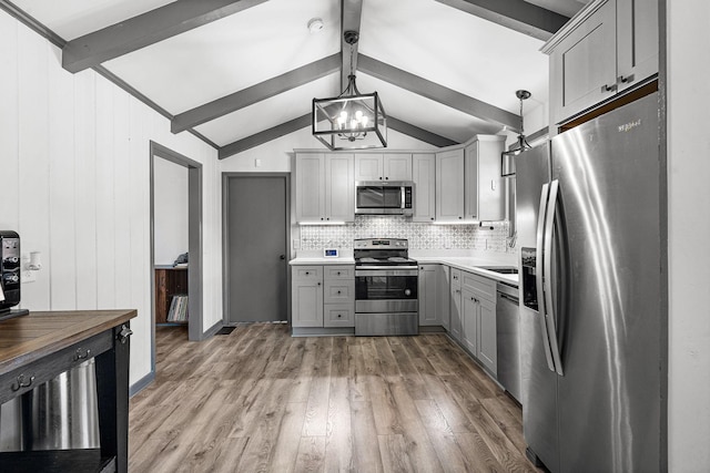 kitchen with stainless steel appliances, gray cabinetry, butcher block countertops, and decorative light fixtures