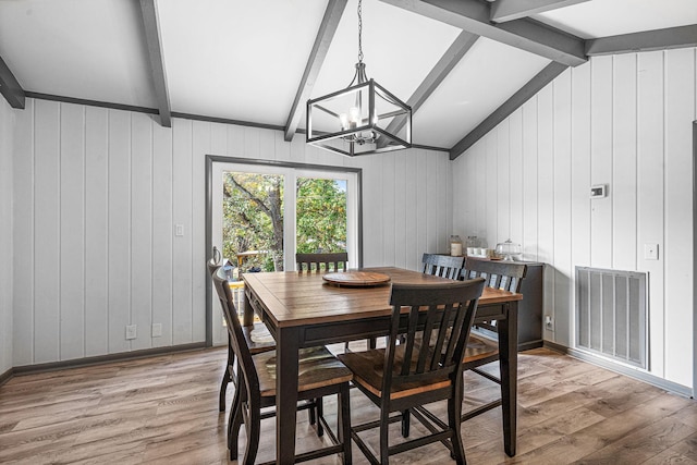 dining space featuring wooden walls, a chandelier, light hardwood / wood-style flooring, and vaulted ceiling with beams