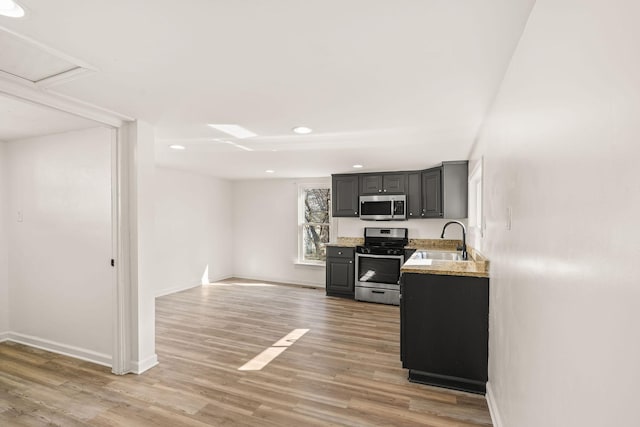 kitchen featuring stainless steel appliances, sink, light hardwood / wood-style floors, and gray cabinets