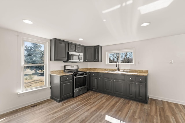 kitchen with stainless steel appliances, hardwood / wood-style flooring, gray cabinets, and sink