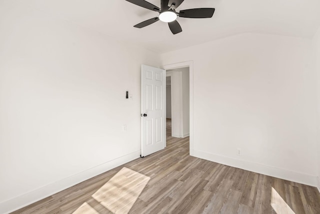 empty room with light hardwood / wood-style flooring, ceiling fan, and vaulted ceiling