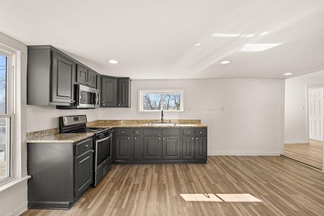 kitchen with gray cabinets, appliances with stainless steel finishes, sink, and light stone counters