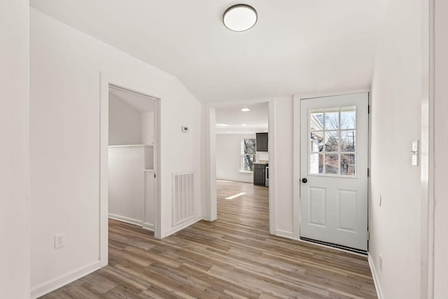 foyer entrance with light hardwood / wood-style floors and vaulted ceiling