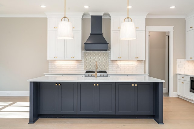 kitchen featuring custom exhaust hood, range, pendant lighting, a kitchen island with sink, and white cabinets