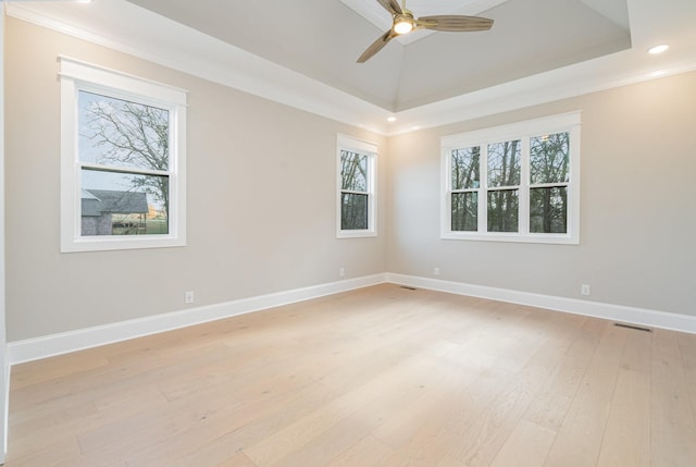 empty room featuring a tray ceiling, ornamental molding, light hardwood / wood-style floors, and ceiling fan