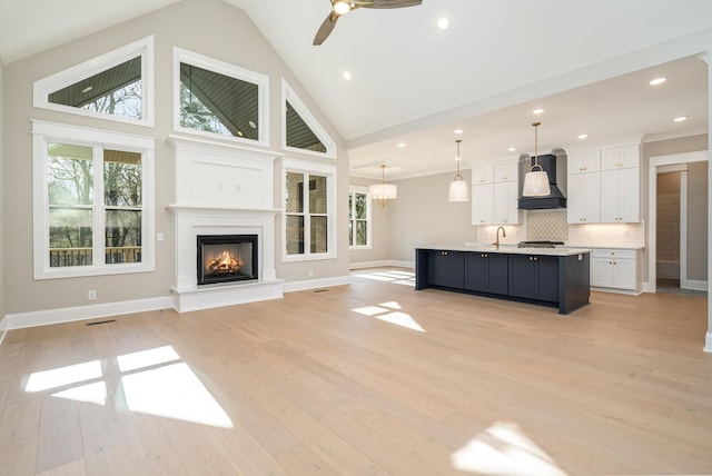 unfurnished living room featuring ceiling fan, sink, light hardwood / wood-style floors, and high vaulted ceiling