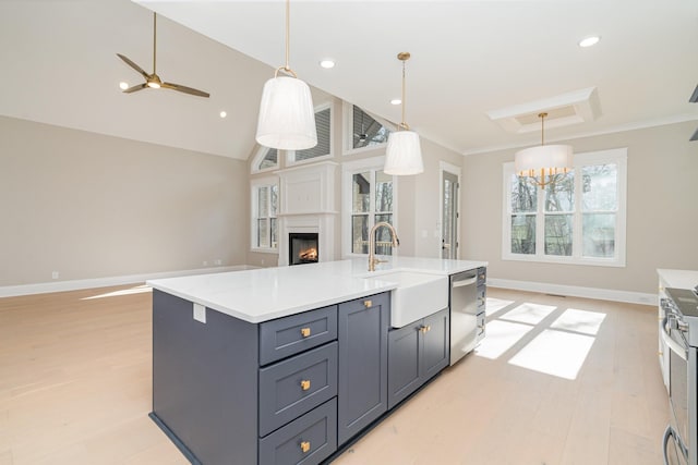 kitchen featuring sink, hanging light fixtures, a center island with sink, stainless steel appliances, and a fireplace