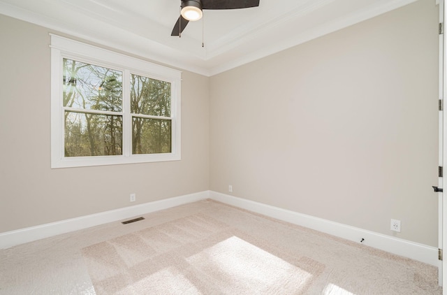 unfurnished room featuring a tray ceiling, ornamental molding, light colored carpet, and ceiling fan