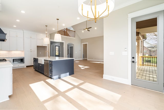 kitchen with pendant lighting, built in microwave, an island with sink, tasteful backsplash, and white cabinets