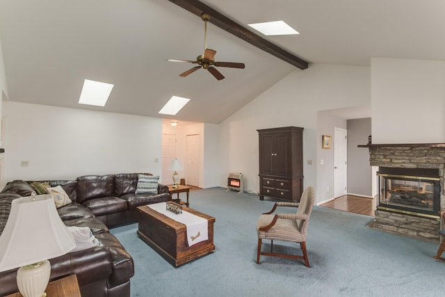 carpeted living area featuring high vaulted ceiling, beam ceiling, a skylight, a fireplace, and ceiling fan