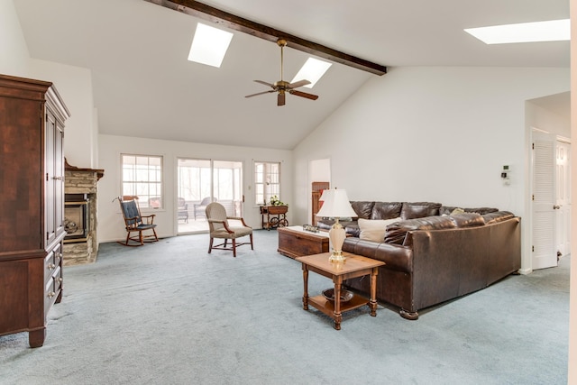 living room featuring light carpet, beamed ceiling, a fireplace, and a skylight