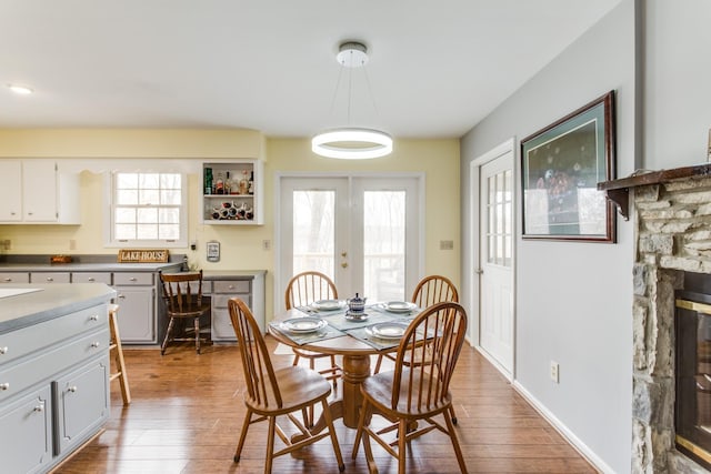 dining space with hardwood / wood-style flooring, a fireplace, and french doors