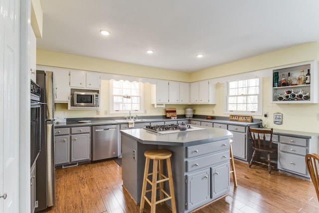 kitchen featuring hardwood / wood-style floors, dark countertops, appliances with stainless steel finishes, and gray cabinetry