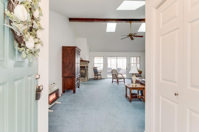 interior space featuring ceiling fan, light colored carpet, vaulted ceiling with skylight, and heating unit