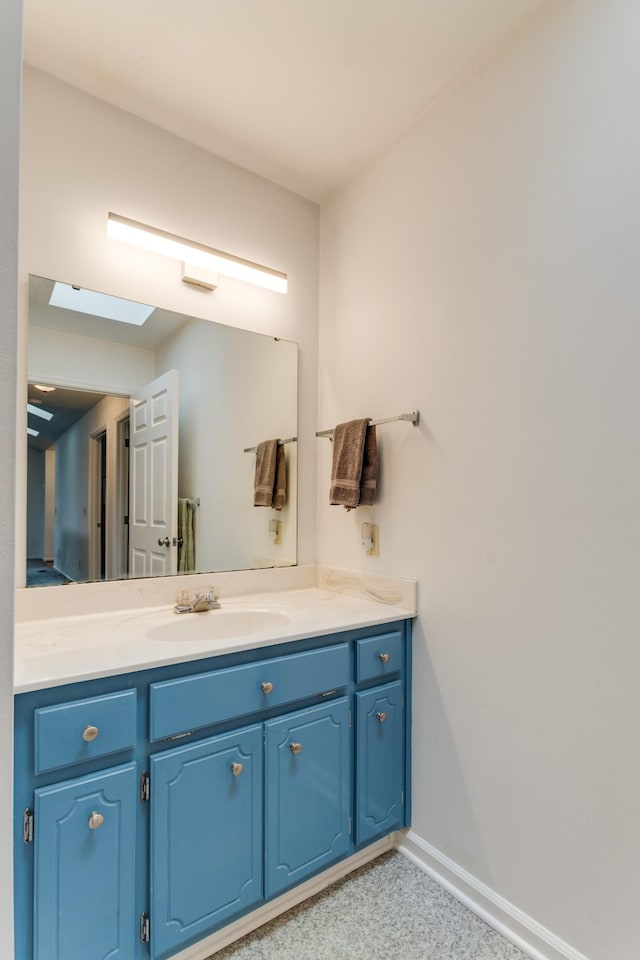 bathroom with baseboards, a skylight, and vanity