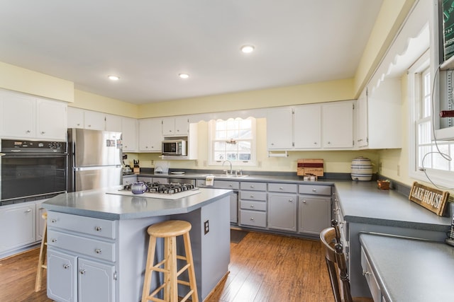 kitchen featuring white cabinetry, a center island, dark wood finished floors, gray cabinets, and stainless steel appliances