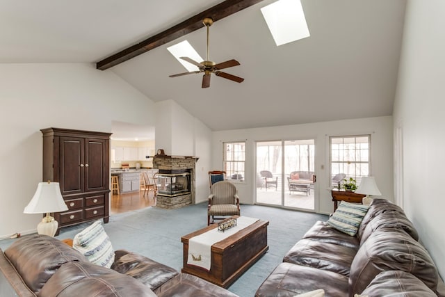 living room featuring light colored carpet, beam ceiling, a fireplace, a skylight, and high vaulted ceiling