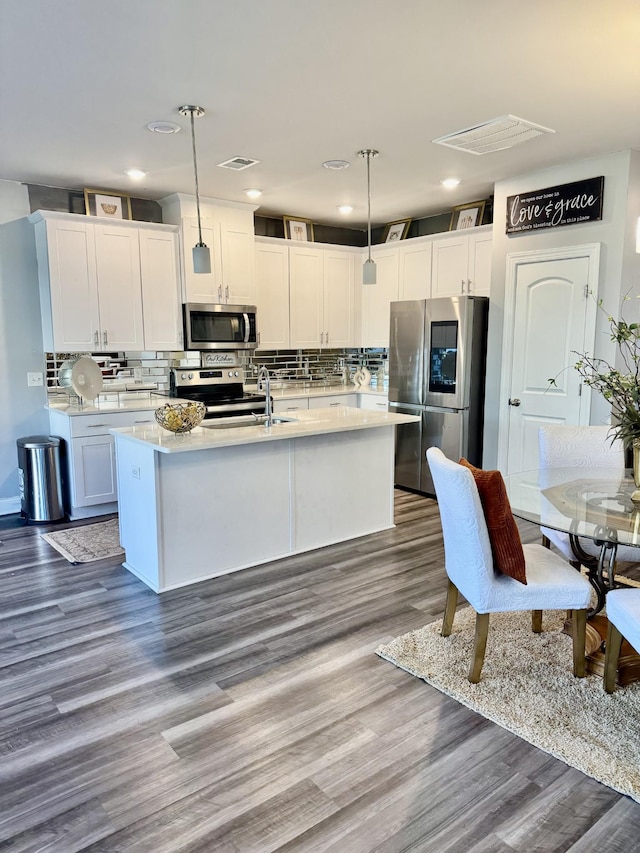 kitchen featuring decorative light fixtures, wood-type flooring, white cabinets, and appliances with stainless steel finishes